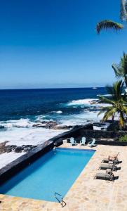 uma piscina com cadeiras e o oceano em Kona Tiki Hotel em Kailua-Kona