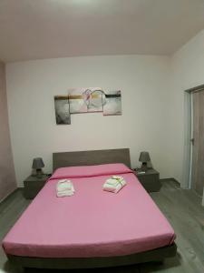a pink bed with two towels on top of it at Casa vacanza Viola in Trapani