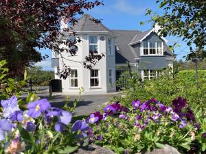 a white house with flowers in front of it at Tailors Lodge, Luxurious peaceful Apartment- Castleisland, Kerry in Castleisland