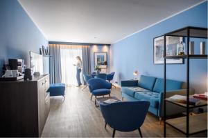 a woman standing in a living room with a blue couch at Holiday Inn Lübeck by IHG in Lübeck