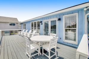 a deck with a white table and white chairs at Belle Mare in Folly Beach