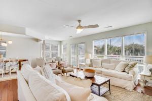 a living room with white furniture and windows at Belle Mare in Folly Beach