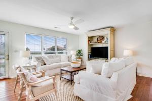 a living room with white furniture and a flat screen tv at Belle Mare in Folly Beach +35 photos