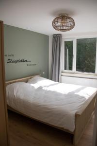 a bed in a bedroom with a sign on the wall at Naanhover Beemden in Nuth