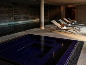 a pool in a hotel with lounge chairs next to it at LeCrans in Crans-Montana