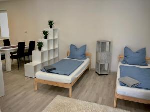 2 Betten mit blauen Kissen in einem Zimmer mit Tisch in der Unterkunft Apartmány Zahrádky in Hráz
