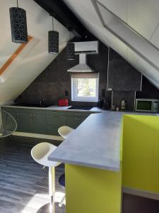 eine Küche mit grünen Schränken und einer Theke mit Stühlen in der Unterkunft Studio neuf côté campagne agréable à vivre. in Braine-le-Comte
