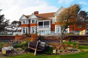 une grande maison avec un bateau dans la cour dans l'établissement The Beach House, à Milford on Sea