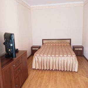 a bedroom with a bed and a tv on a dresser at Автор, номера и отдельный коттедж in Anapa