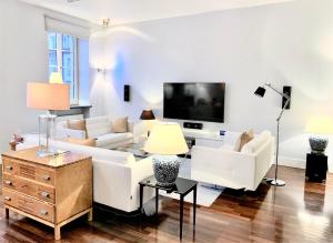 een woonkamer met witte meubels en een flatscreen-tv bij MONDRIAN Luxury Suites & Apartments Old Town in Warschau