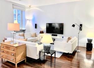 a living room with white furniture and a flat screen tv at MONDRIAN Luxury Suites & Apartments Old Town in Warsaw