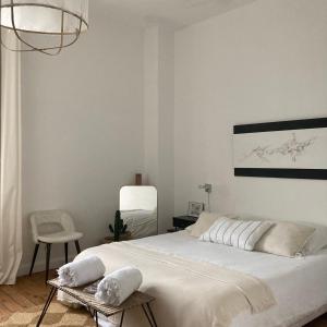 um quarto com uma grande cama branca e uma cadeira em la boutique mj décoration vous propose de découvrir ses deux chambres d'hôtes em Doué-la-Fontaine