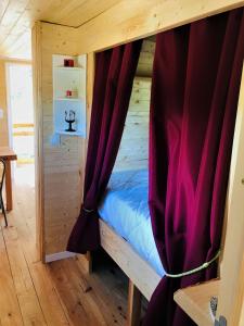 a bed in a wooden room with a curtain at ROULOTTE DE CHARME in Saint-Genest-de-Bauzon