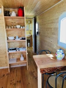 Habitación con paredes de madera, mesa y sillas. en ROULOTTE DE CHARME, en Saint-Genest-de-Bauzon