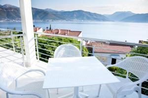 einen weißen Tisch und Stühle auf einem Balkon mit Blick auf das Wasser in der Unterkunft Boka 2 in Krasići