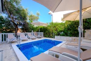 a pool with chairs and umbrellas next to a house at Boka 2 in Krasici