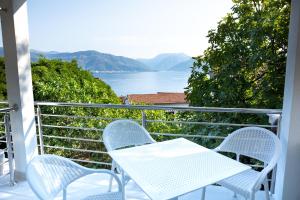 una mesa blanca y sillas en un balcón con vistas al agua en Boka 2, en Krasići
