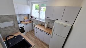 a kitchen with white cabinets and a white refrigerator at Apartament Gdańsk Stogi plaża centrum 2024 in Gdańsk