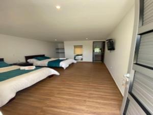 Duas camas num quarto grande com pisos de madeira em Hotel Takuara em Vergara