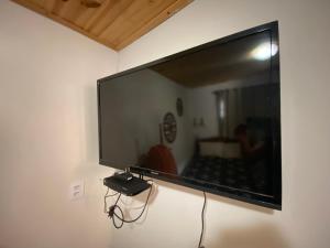 Elle comprend une grande télévision à écran plat suspendue au mur. dans l'établissement Chalé Flor da Serra, à Conceição da Ibitipoca