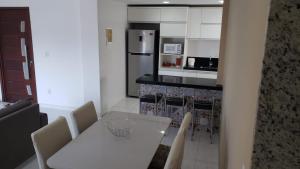 eine Küche mit einem weißen Tisch und Stühlen sowie einer Theke in der Unterkunft Apartamento Novo em Itaúna, Maracanã do Surf in Saquarema