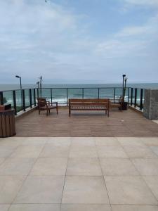 two benches sitting on a pier looking at the ocean at Conforto em Condomínio Frente Mar in Barra Velha
