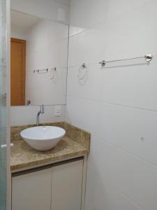 a bathroom with a white sink and a mirror at Conforto em Condomínio Frente Mar in Barra Velha