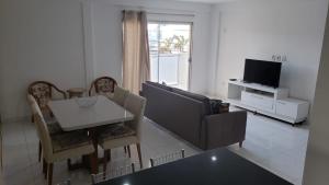 ein Wohnzimmer mit einem Tisch, einem Sofa und einem TV in der Unterkunft Apartamento Novo em Itaúna, Maracanã do Surf in Saquarema
