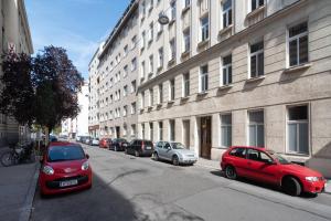 eine Reihe von Autos, die auf einer Straße neben einem Gebäude geparkt sind in der Unterkunft Vienna Living Apartments - Raffaelgasse in Wien