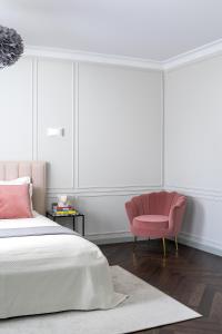 a bedroom with a bed and a pink chair at Place No. 2 in Vilnius
