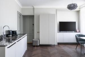a kitchen with white cabinets and a flat screen tv at Place No. 2 in Vilnius