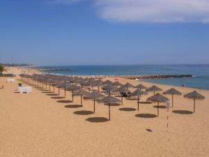 a row of umbrellas on a beach with the ocean at Residencial Nosso Paraiso in Quarteira