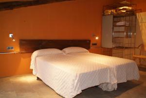 1 dormitorio con cama blanca y pared de color naranja en Hotel rural Font del Genil en Arsèguel