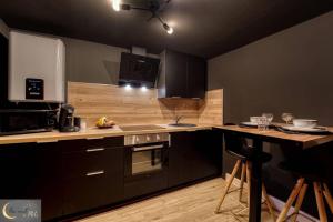 a kitchen with black cabinets and a counter top at La chambre noire au coeur de Metz (unenuitametz) in Metz