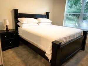 um quarto com uma cama grande com lençóis brancos e almofadas em Upscale Condo Full Kitchen Balcony Rooftop Pool em Jacksonville