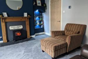 a living room with a chair and a fireplace at Duck & Heron Cottage in Morpeth