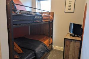 a room with two bunk beds and a television at Duck & Heron Cottage in Morpeth