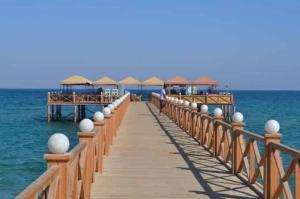 a wooden pier with umbrellas on the water at شاليه أرضي بجنينه في مارينا وادي دجله العين السخنه Three Bedroom Chalet with Garden In Marina Wadi Degla Ain El Sokhna - For Families Only in Ain Sokhna