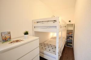 a white bunk bed in a small room with a desk at Ferienwohnung Gustav - Moderne Maisonette-Wohnung mit Terrasse in Wangerooge