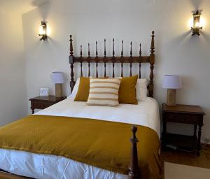 um quarto com uma cama grande com lençóis amarelos e 2 candeeiros em Pátio da Muralha em Óbidos