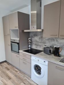 a white kitchen with a washing machine in it at Le doux sapin in Lembach