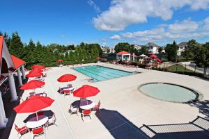 a swimming pool with red umbrellas and chairs and a pool at Bethany Lakes - 31292 May in Bethany Beach
