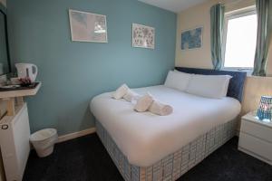 een slaapkamer met een wit bed en handdoeken bij Irvine Riverside Guesthouse by Paymán Club in Irvine