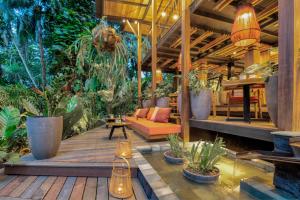a patio with plants and a couch on a wooden deck at aWà Beach Hotel in Puerto Viejo