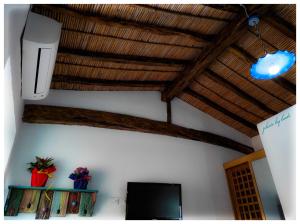 a living room with a television and a wooden ceiling at La casetta in Dorgali