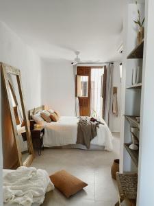 Habitación blanca con cama y espejo en Hospedería Boutique Albariza by La Judería De Vejer- ADULTS ONLY en Vejer de la Frontera