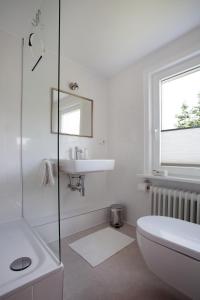 uma casa de banho branca com um lavatório e um WC em Lohmann`s em Garstedt