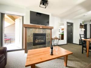 a living room with a fireplace and a table at UPPER VILLAGE - 2BD condo steps to Main Pools and Hill in Panorama