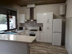 uma cozinha com armários brancos e um frigorífico branco em Casas Rurales Huerto Del Abuelito em Valdeganga
