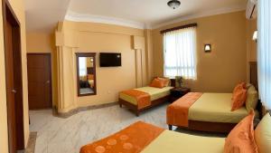 una camera d'albergo con due letti e uno specchio di Hostal California Inn a Guayaquil